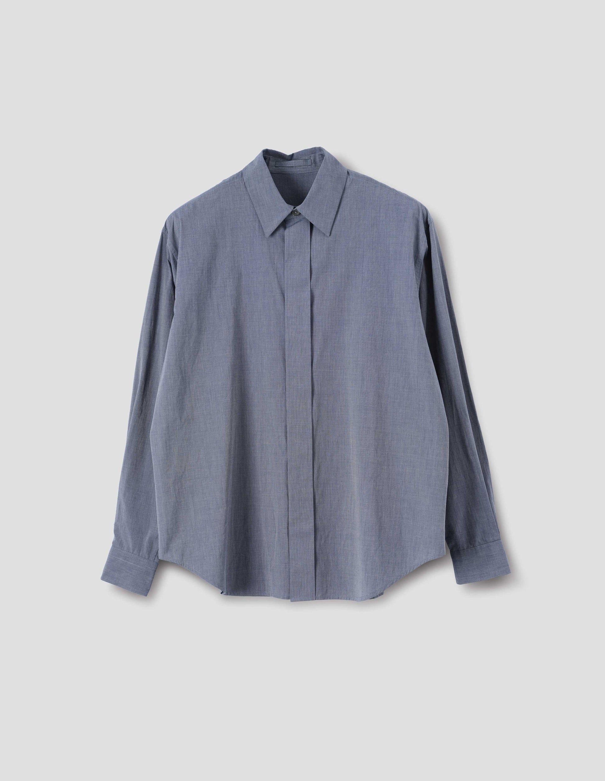 Blue cotton shirt with concealed button placket and mother of pearl button on collar, hanger loop on back neck and curved hem. Front flat lay view.