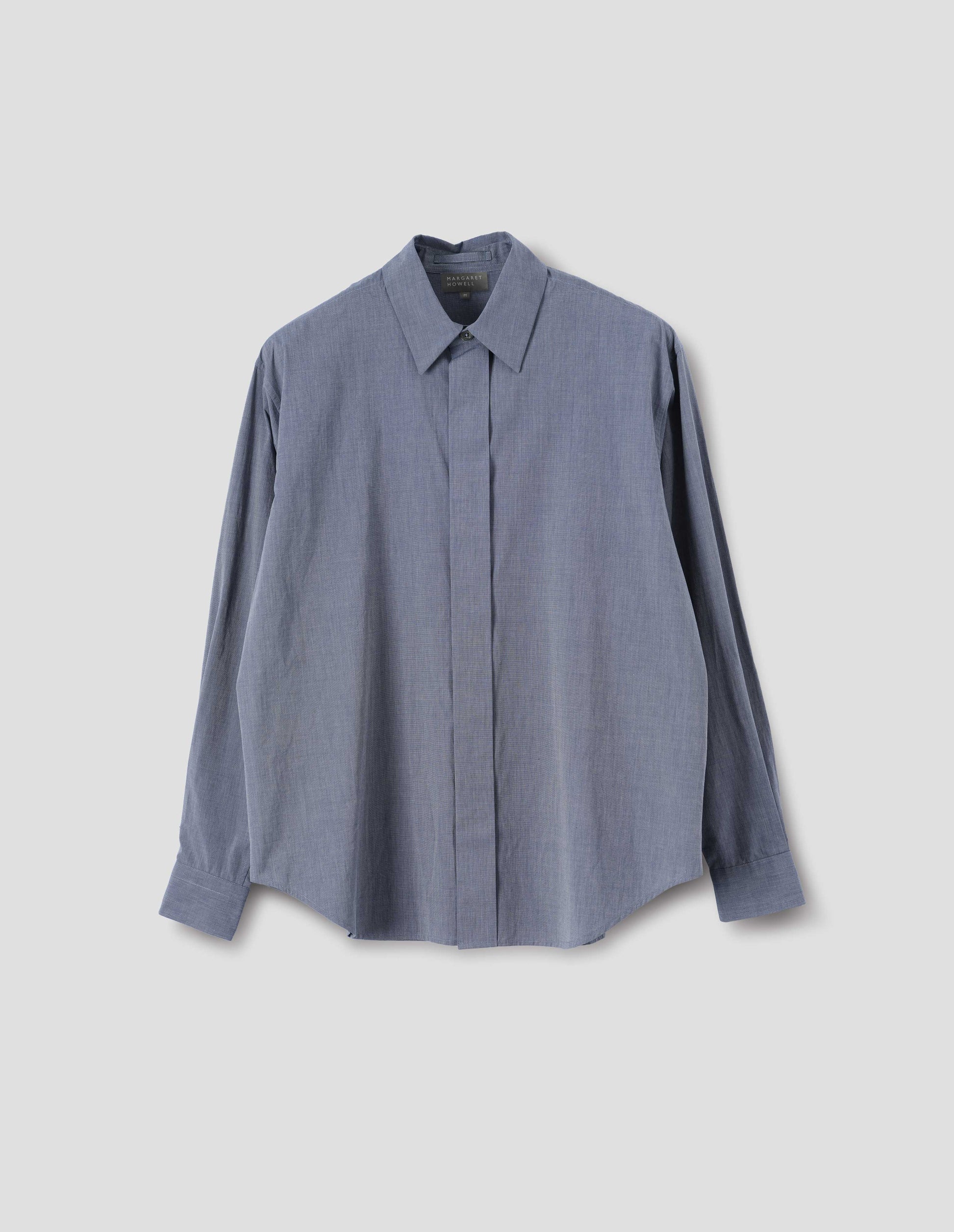 Blue cotton shirt with concealed button placket and mother of pearl button on collar, hanger loop on back neck and curved hem. Front flat lay view.