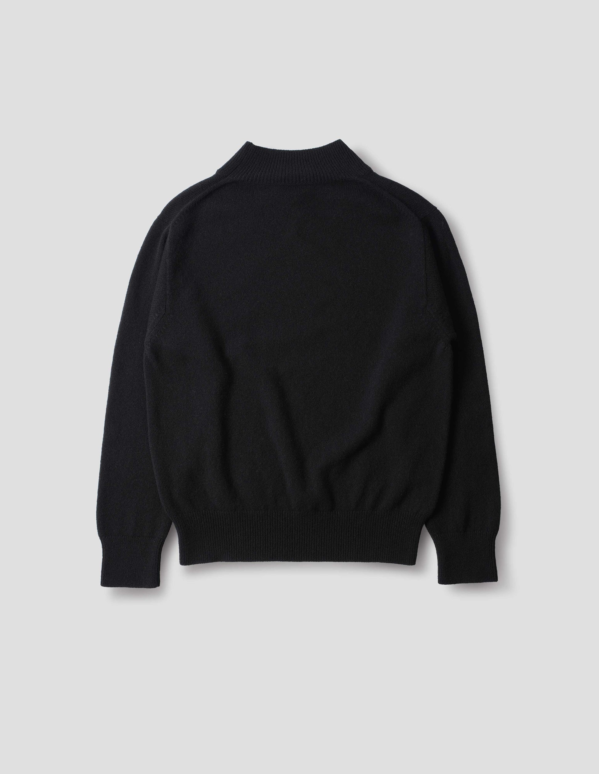 Black fully fashioned seamless wool jumper with rib mock neck, set-in sleeves, and ribbed cuffs and hem. Back flat lay view.