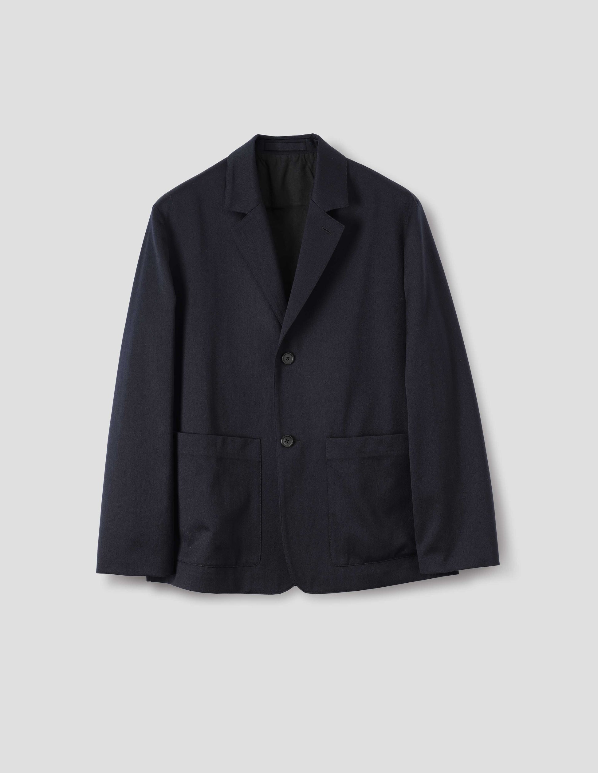 Dark blue wool cotton blazer with dropped shoulders, horn buttons and deep patch pockets. Front flat lay view.