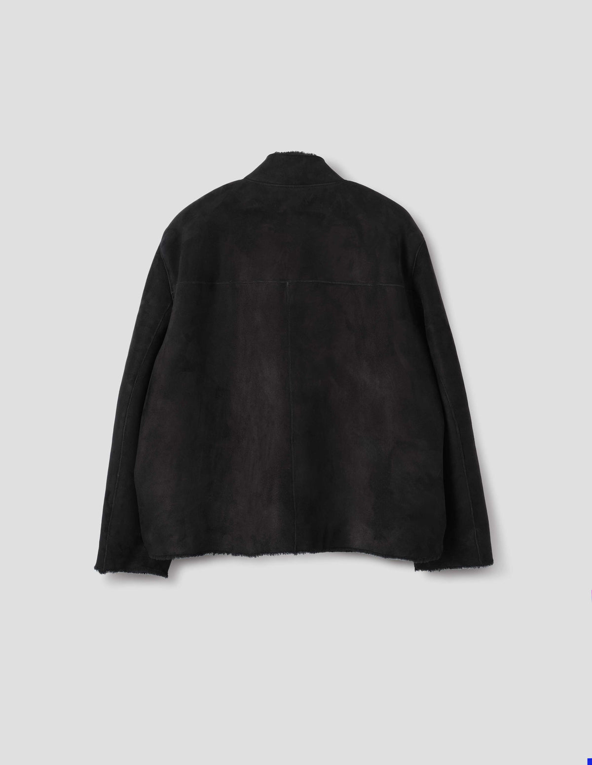 Black sheepskin jacket with partial funnel neck, back yoke with a centre back seam and with raw edges on neck, sleeves and hem. Back flat lay view.