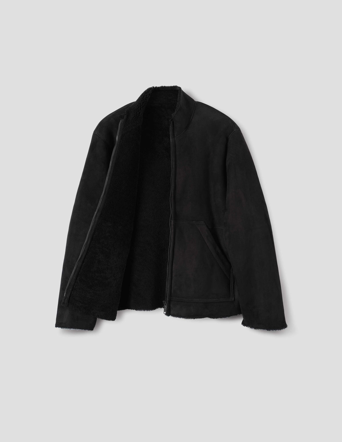 Black sheepskin jacket with zip-through front, partial funnel neck with raw edge, slanted front half kangaroo pockets, raw edges on sleeves and hem, and curly merino inside. Open flat lay view.