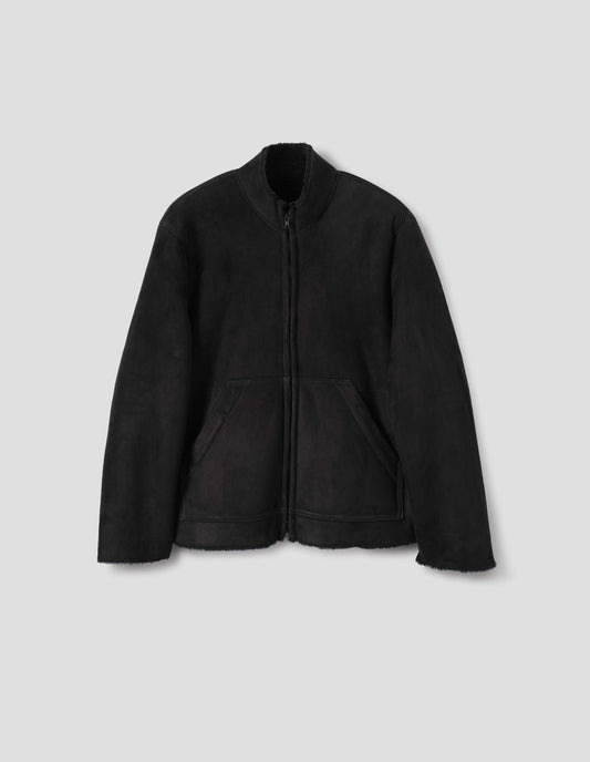 Black sheepskin jacket with zip-through front, partial funnel neck with raw edge, slanted front half kangaroo pockets and raw edges on sleeves and hem. Front flat lay view.
