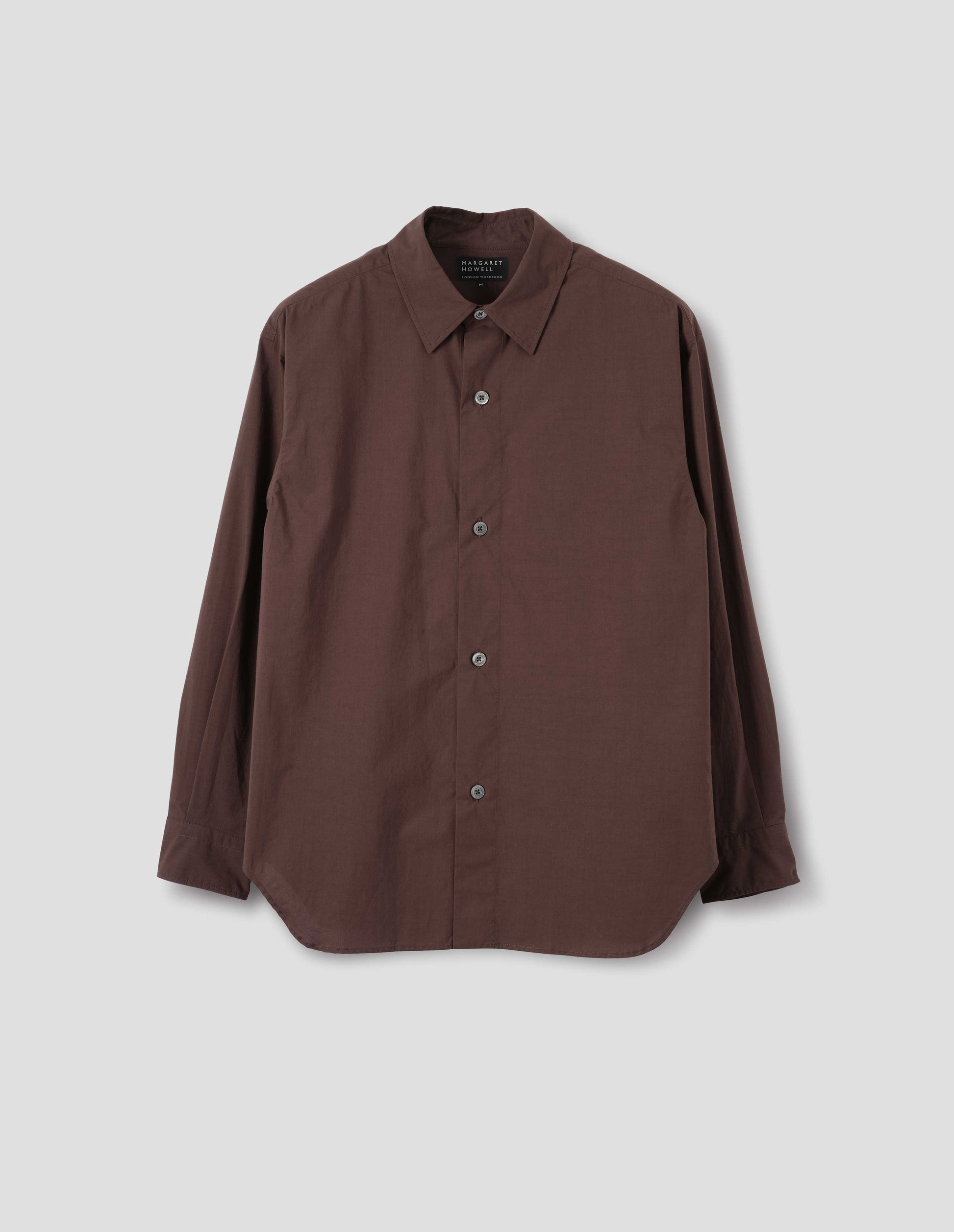 Brown cotton shirt with mother of pearl buttons on wide stitch-through placket and curved hem. Front flat lay view.