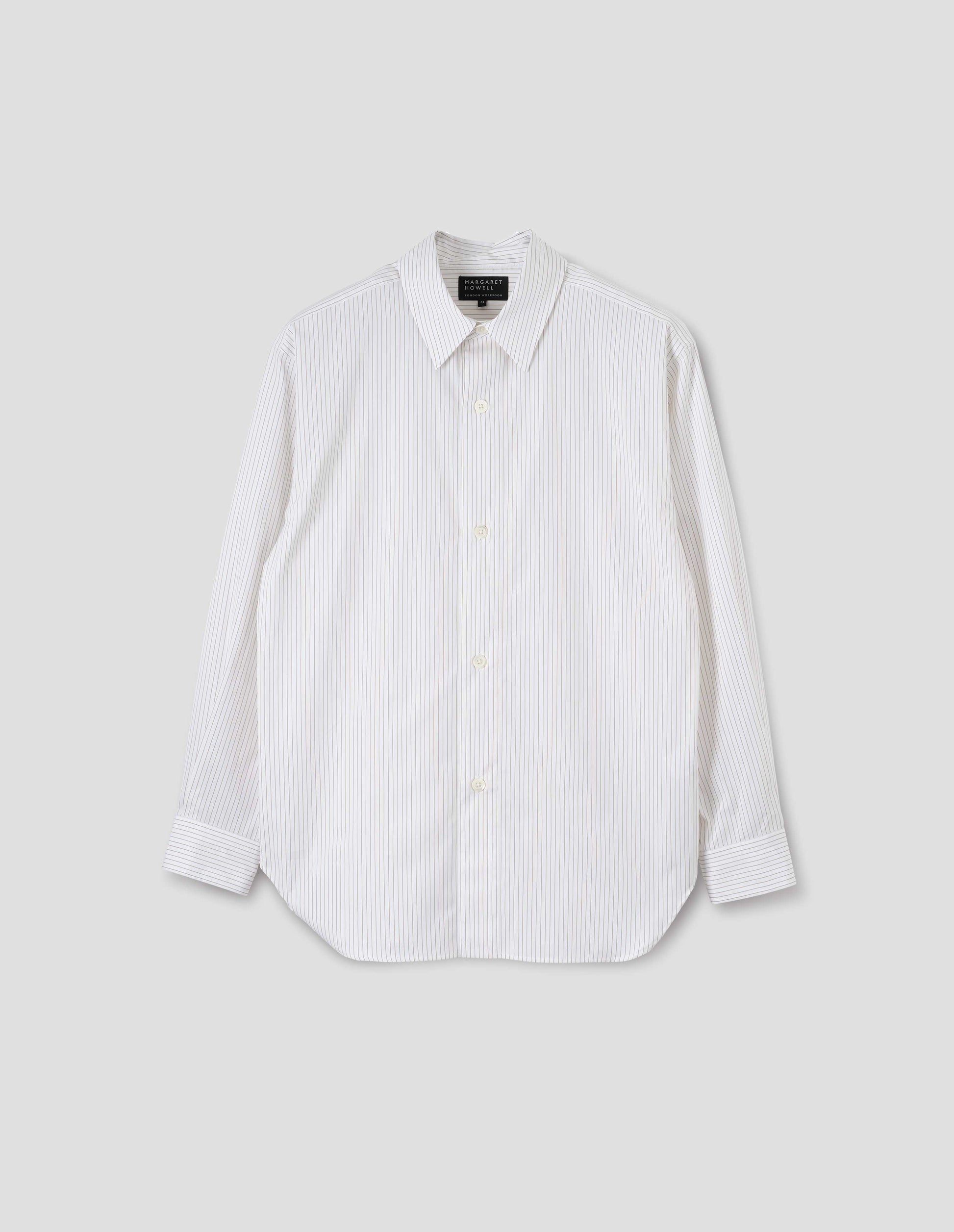 White cotton shirt with green stripes, mother of pearl buttons on wide stitch-through placket and curved hem. Front flat lay view.