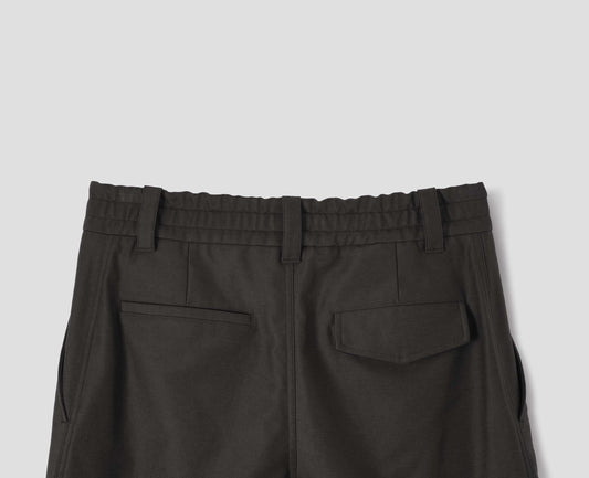 Grey cotton trousers with half-elasticated waistband with belt loops, slant side pockets, and welt and flap back pocket with concealed horn button fastening. Back flat lay view.