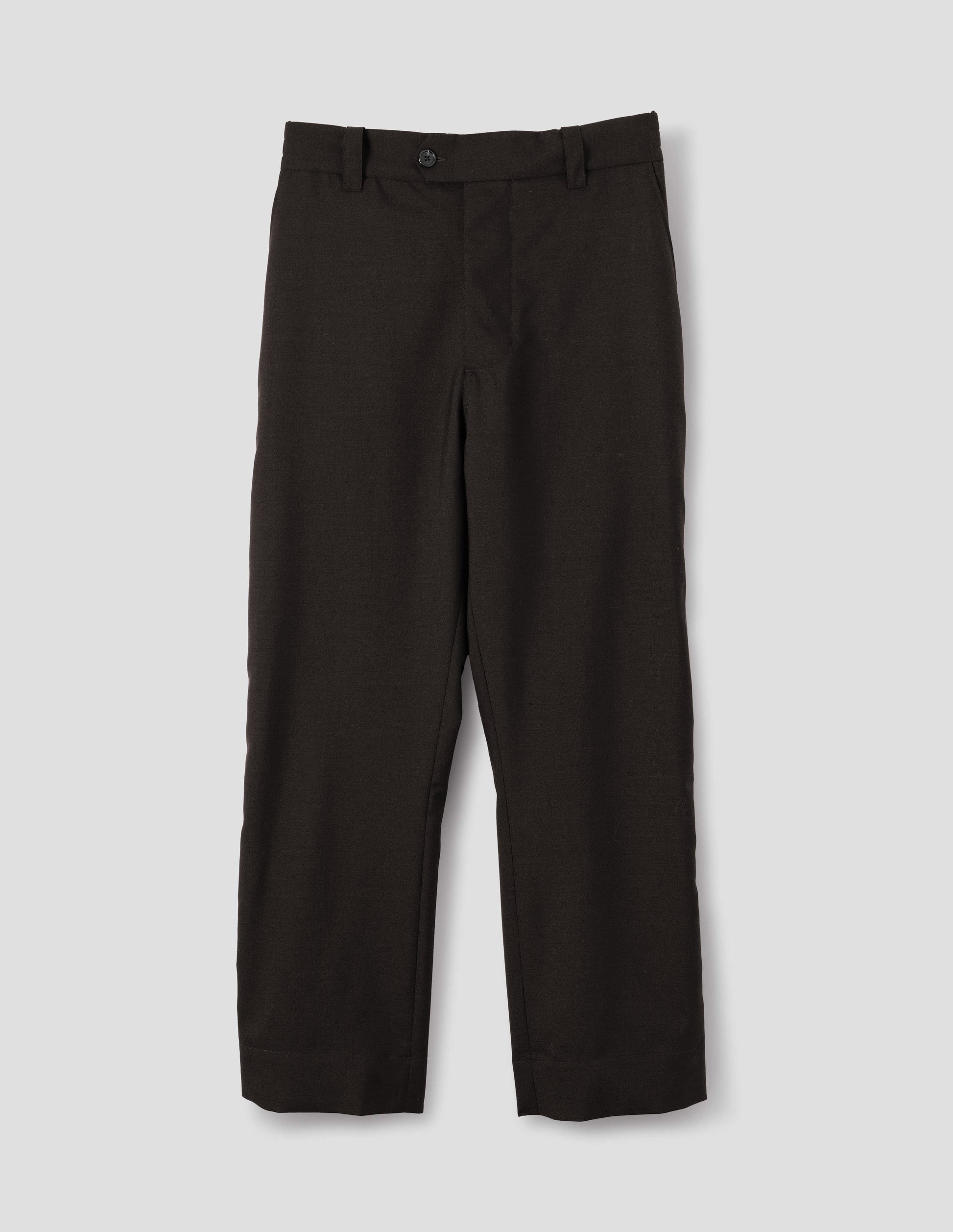 Dark brown wool trousers with half-elasticated extended waistband with belt loops and horn button fastening and slant side pockets. Front flat lay view.