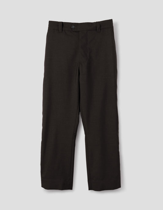 Dark brown wool trousers with half-elasticated extended waistband with belt loops and horn button fastening and slant side pockets. Front flat lay view.
