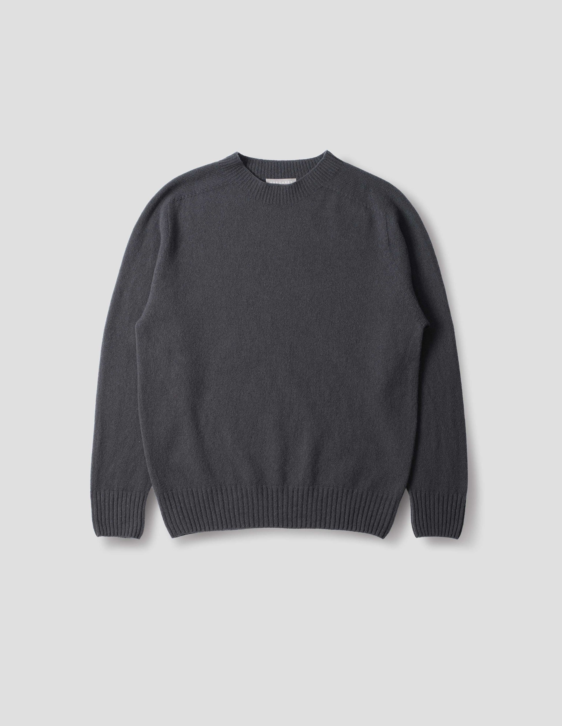 Dark grey merino cashmere seamless jumper with ribbed crew neck, cuffs and hem. Front flat lay view.