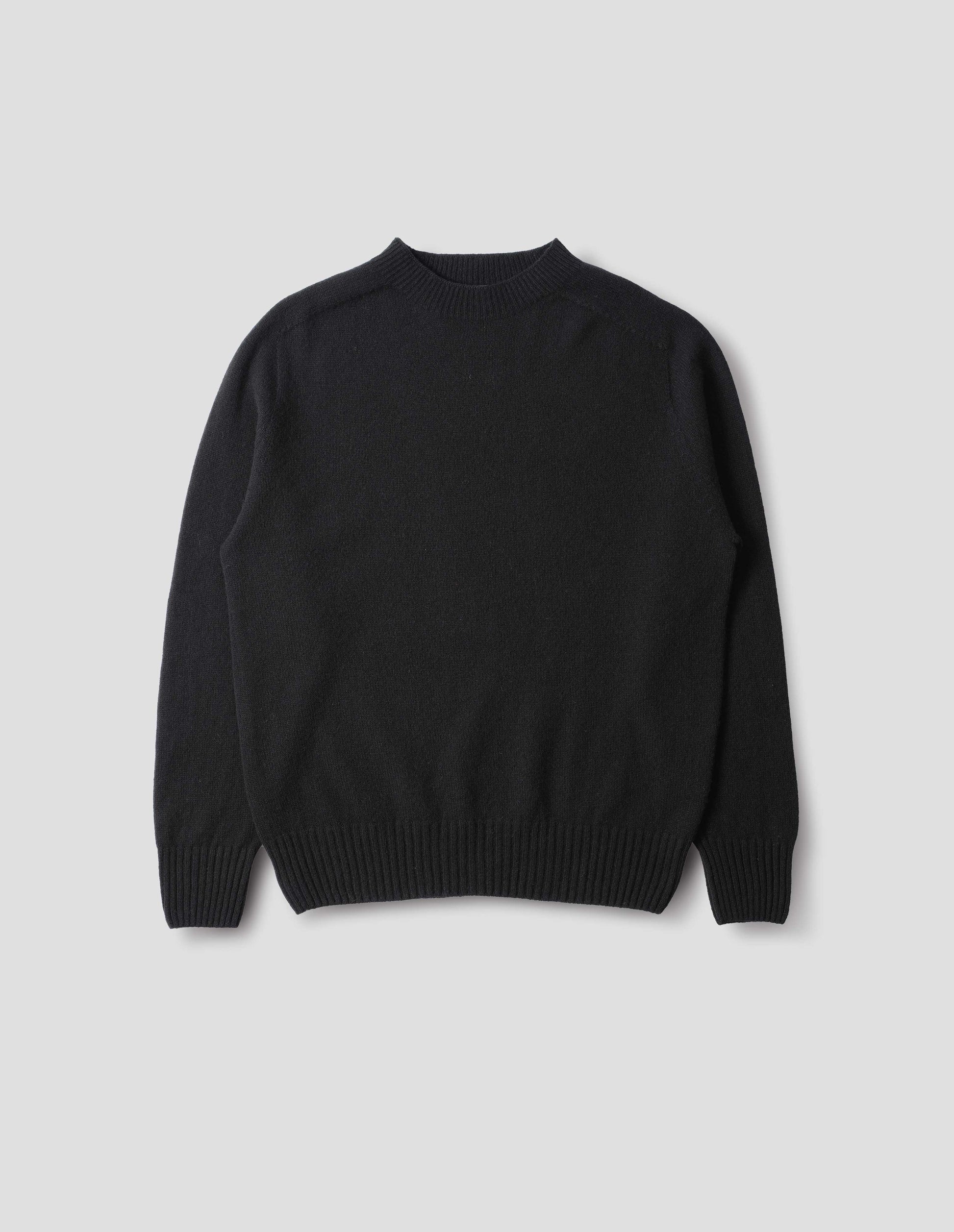 Black merino cashmere seamless jumper with ribbed crew neck, cuffs and hem. Front flat lay view.