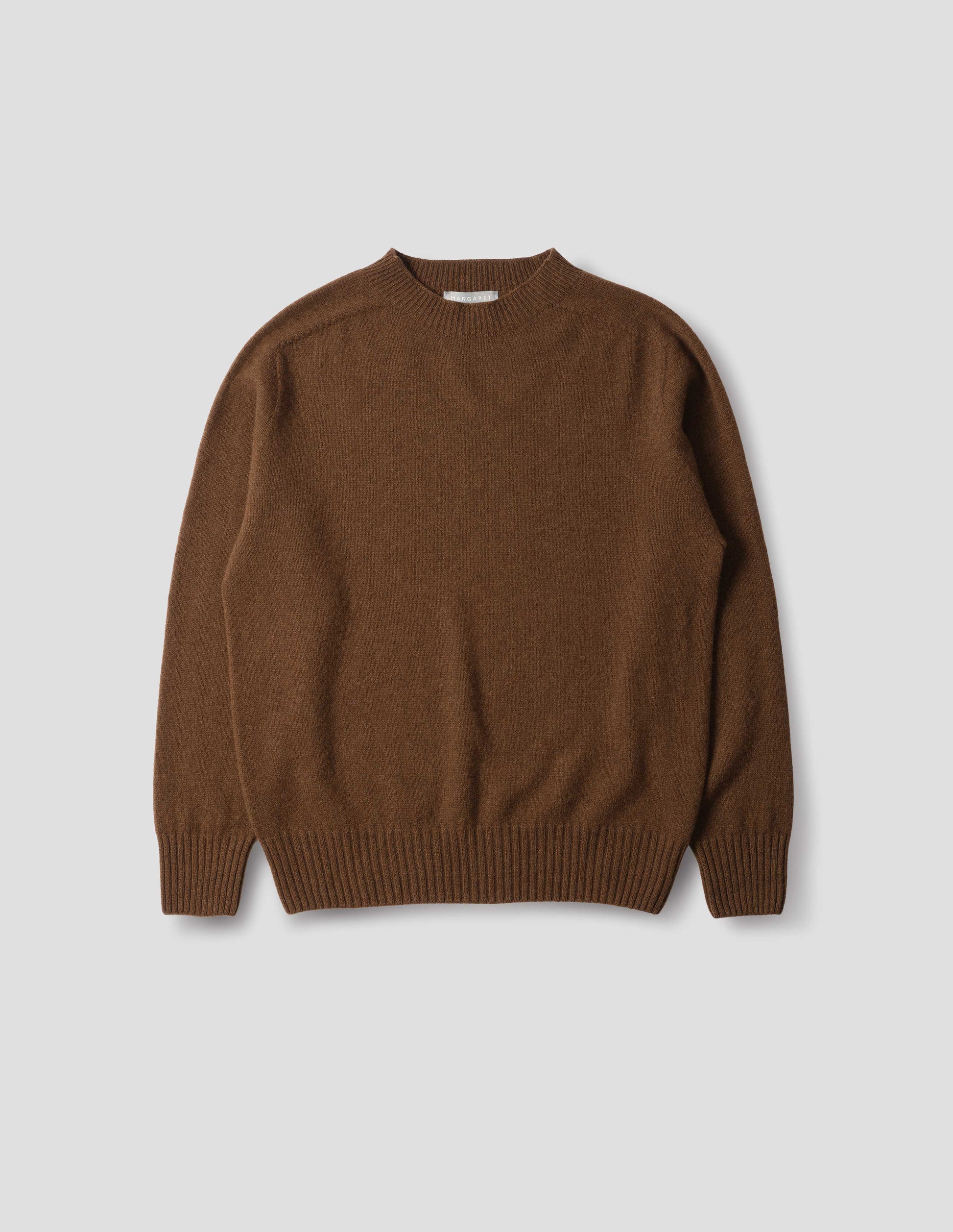 Brown merino cashmere seamless jumper with ribbed crew neck, cuffs and hem. Front flat lay view.