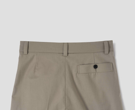 Beige cotton trousers with belt loops and deep horn button-through welt back pocket. Back flat lay view.