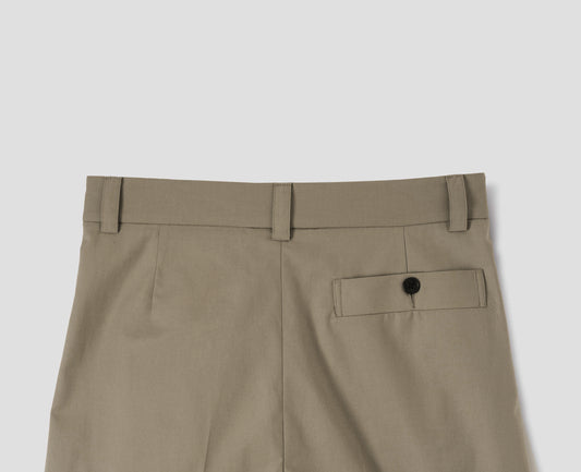 Beige cotton trousers with belt loops and deep horn button-through welt back pocket. Back flat lay view.