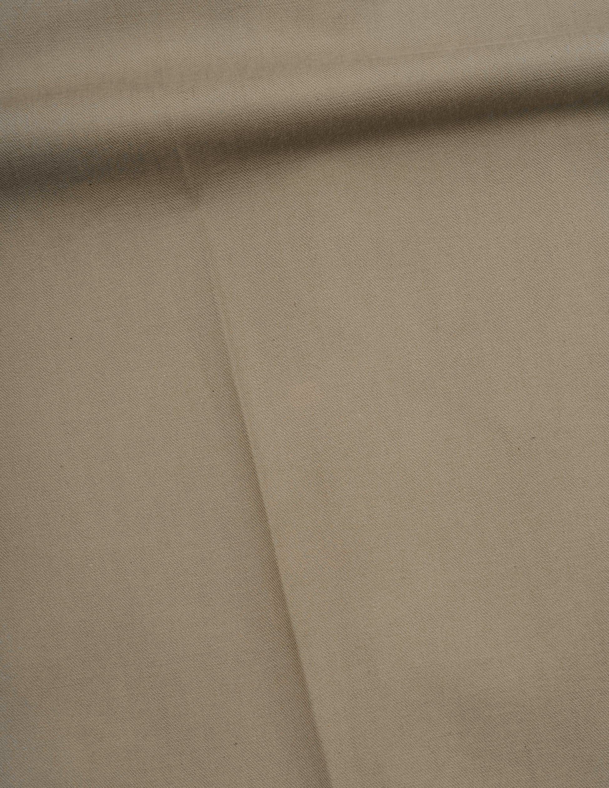 Beige dense cotton drill trousers fabric swatch.