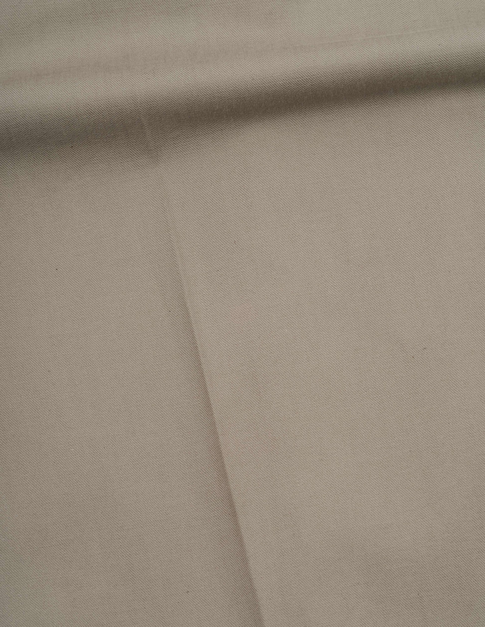 Beige dense cotton drill trousers fabric swatch.