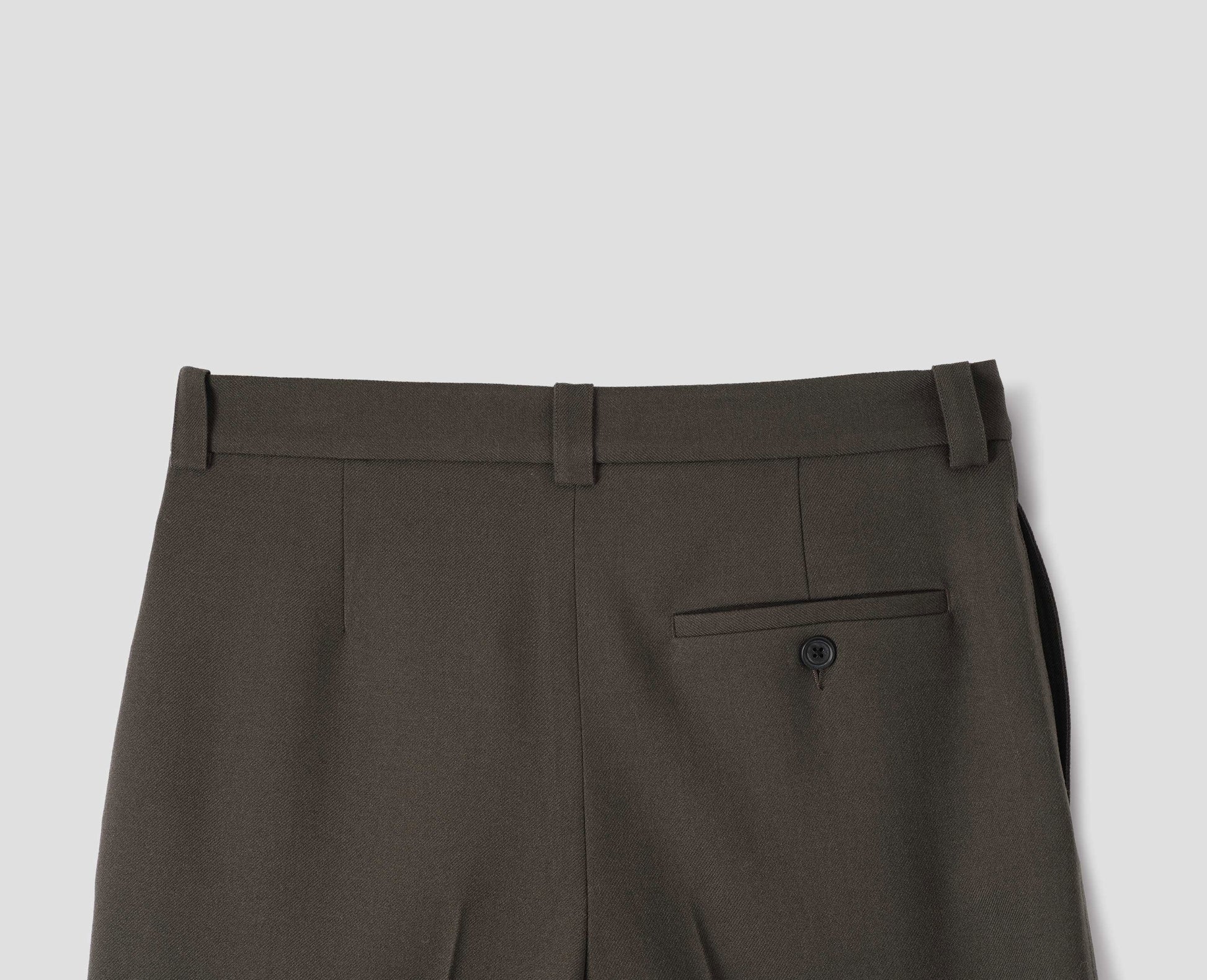 Brown wool trousers with side pockets and horn button-fastening welt back pocket. Back flat lay view.