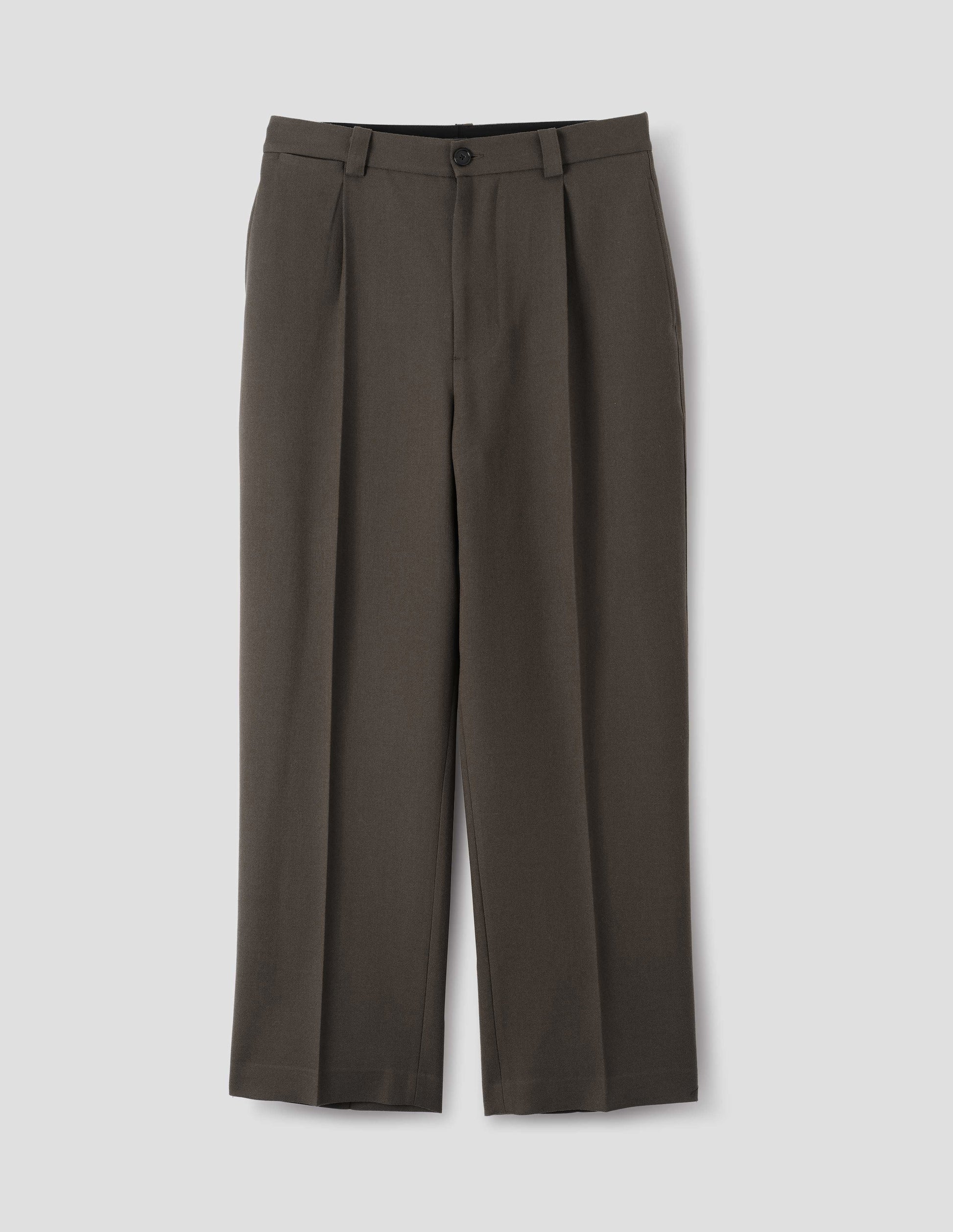 Brown wool trousers with horn button and zip fly fastening, regular belt loops, single pleats, hidden ticket pocket and side pockets. Front flat lay view.