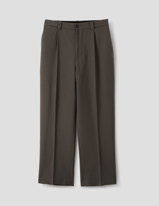 Brown wool trousers with horn button and zip fly fastening, regular belt loops, single pleats, hidden ticket pocket and side pockets. Front flat lay view.