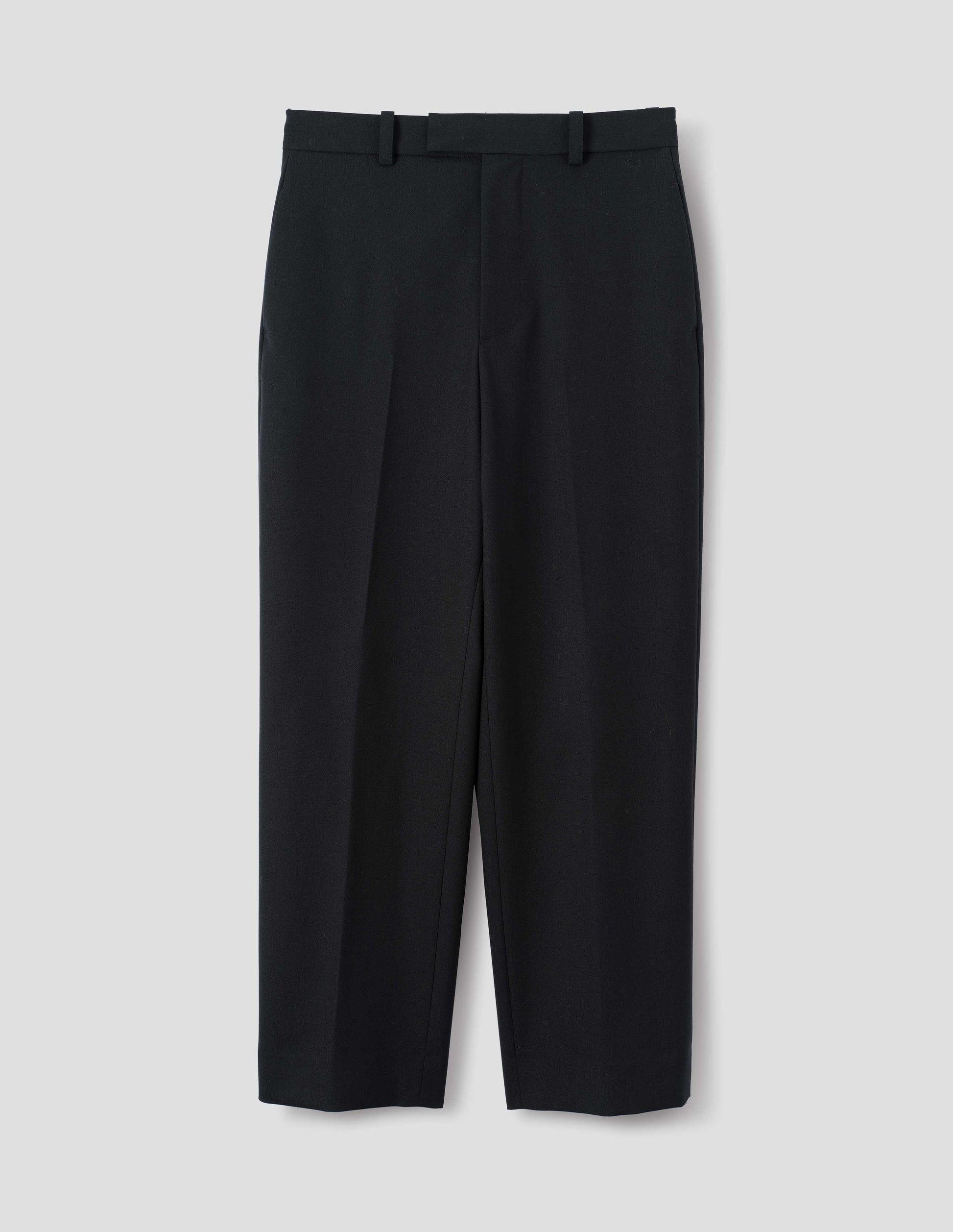 Black wool trousers with belt loops and waistband extension with hook and bar fastening. Front flat lay view.