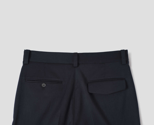 Dark blue wool cotton trousers with belt loops, one jetted flap back pocket and one horn button through jetted back pocket. Back flat way view.