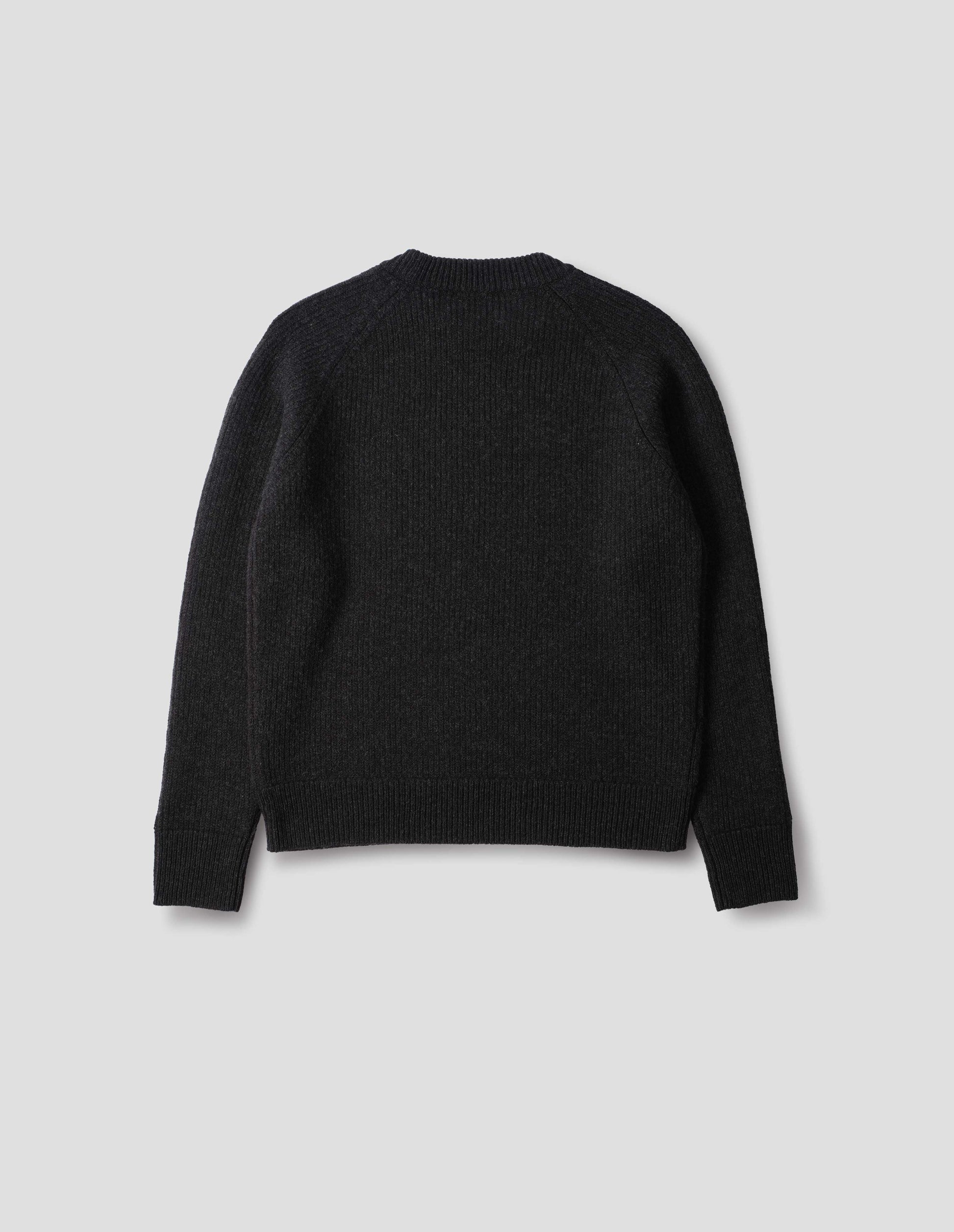 Dark grey wool jumper with raglan sleeves, tubular collar and rib detailing at hem and cuffs. Back flat lay view.