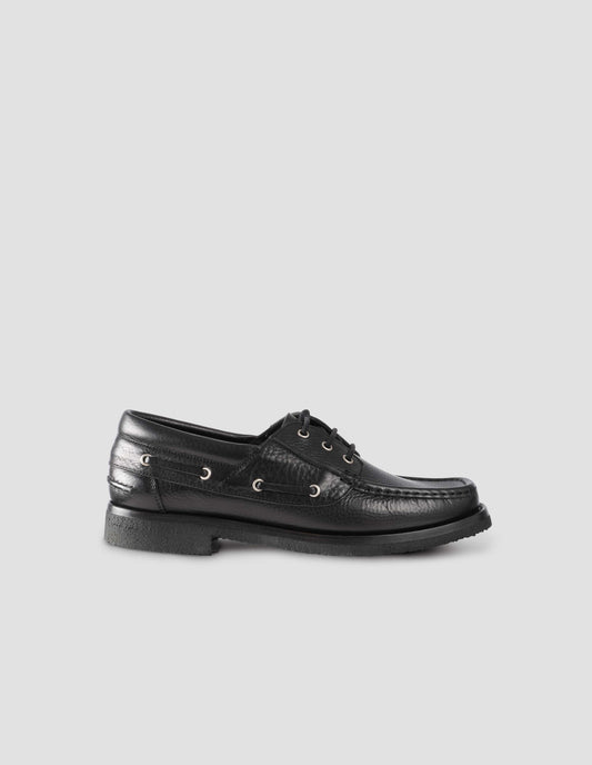 A single black leather deck shoe with padded heel collar and crepe sole. Side view flat lay.