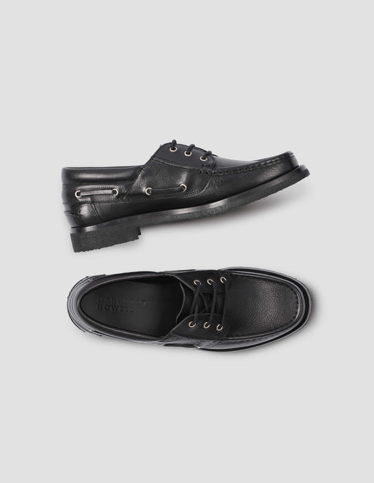 A pair of black leather deck shoe with padded heel collar and crepe sole. View from above flat lay view.