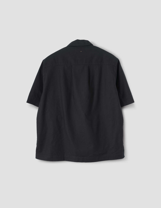 Black textured cotton short sleeve shirt, with side split hem, elongated back and box pleat on back yoke. Back flat lay view.