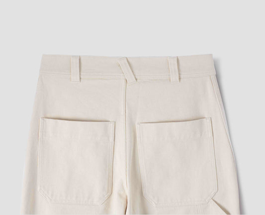 Off white trousers with belt loops and large patch back pockets. Back flat lay view.