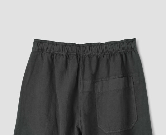 Charcoal grey wide leg trousers, with elasticated waist and  patch back pocket. Back flat lay view.