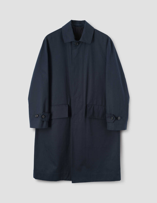 Navy blue longline mac with horn button closure and cuffs and slanted envelope flap pockets, front flat lay view.
