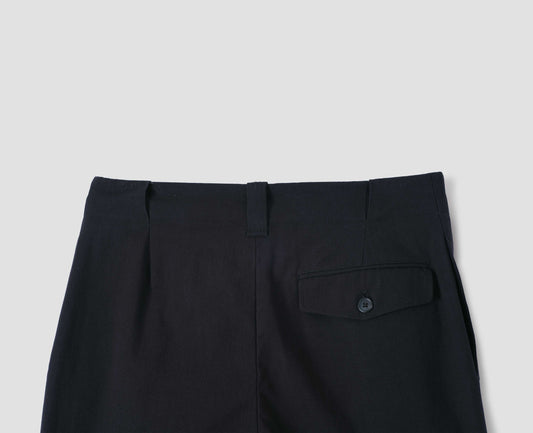 Black single pleated trousers, with wide belt loops and button-through jet flap back pocket. Back flat lay view.
