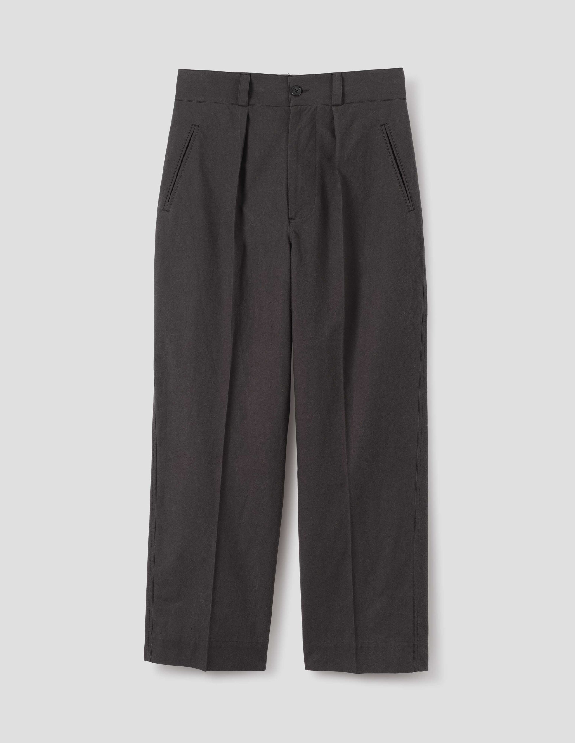 Dark brown cotton trousers with single inverted pleat, deep stitch hem, slant jet pockets and belt loops. Front flat lay view.