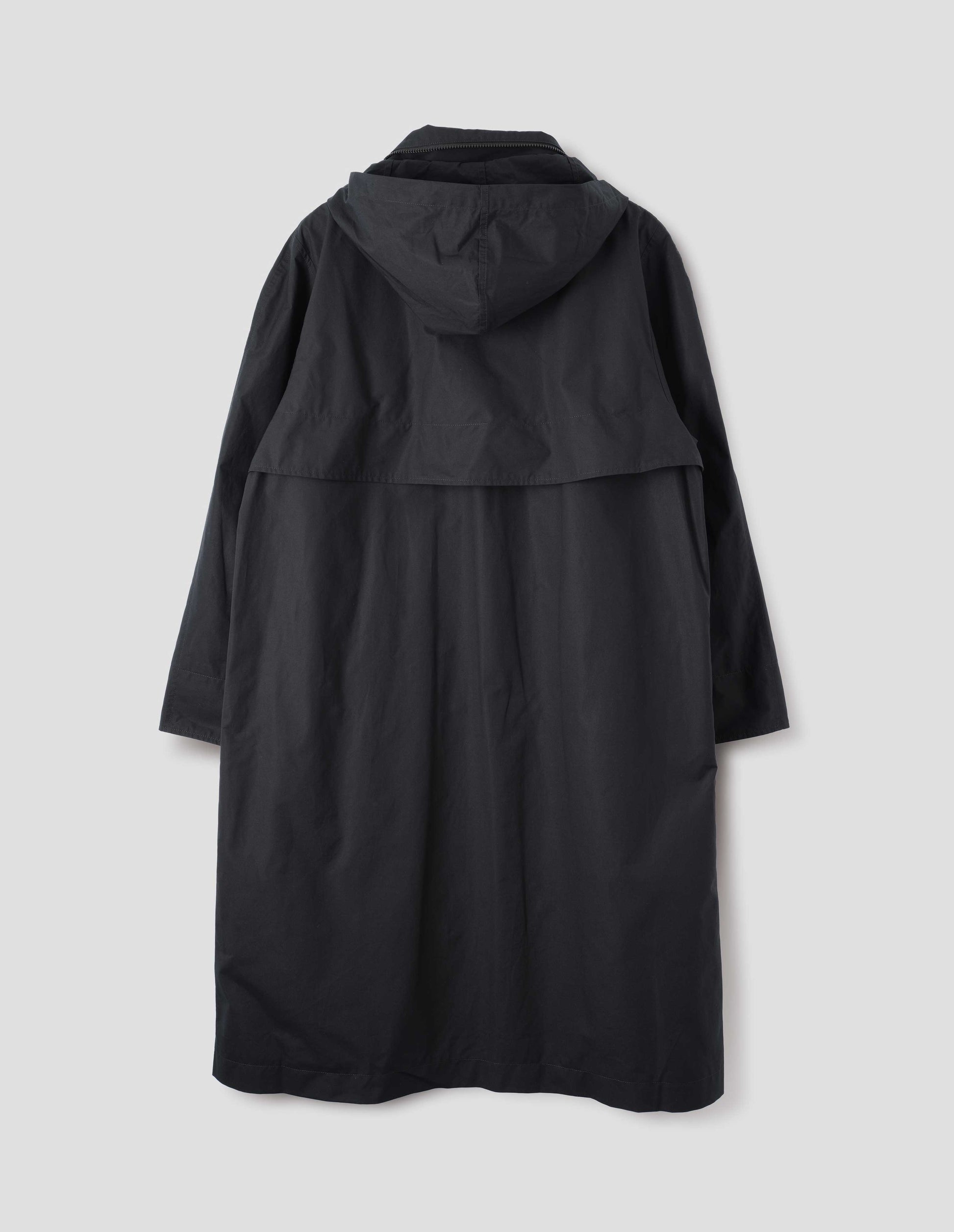 Black ventile cotton poplin longline mac with storm vent and packable hood. Back flat lay view.