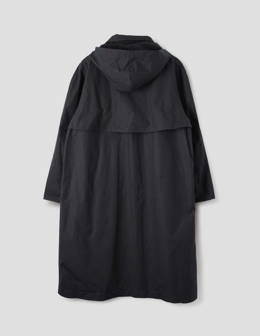 Black ventile cotton poplin longline mac with storm vent and packable hood. Back flat lay view.