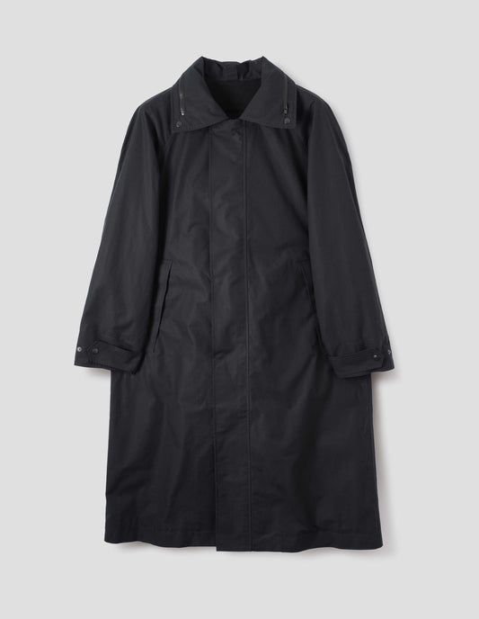 Black ventile cotton poplin longline mac with slant pockets, adjustable popper cuffs and packable hood with contrast black zip detailing on collar. Front flat lay view.