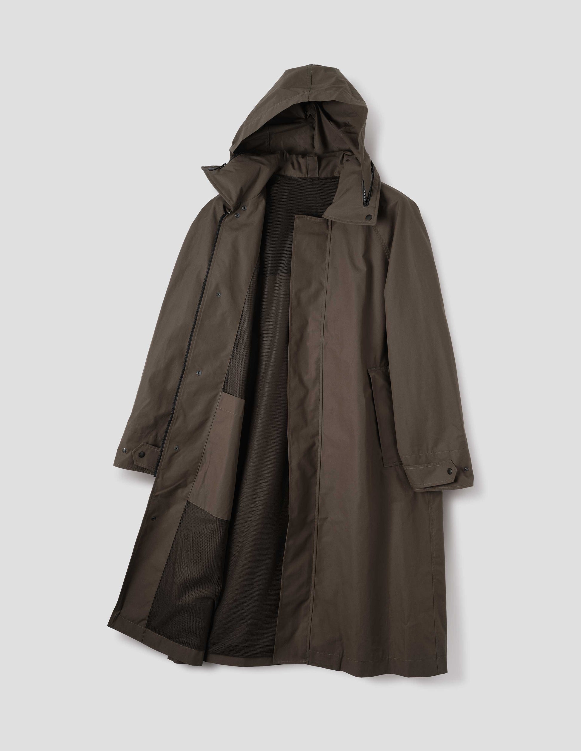 Greenish brown ventile cotton poplin longline mac with contrasting black zip closure, slant pockets, adjustable popper cuffs, contrasting green lining, internal patch pocket and packable hood. Front flat lay open view. 