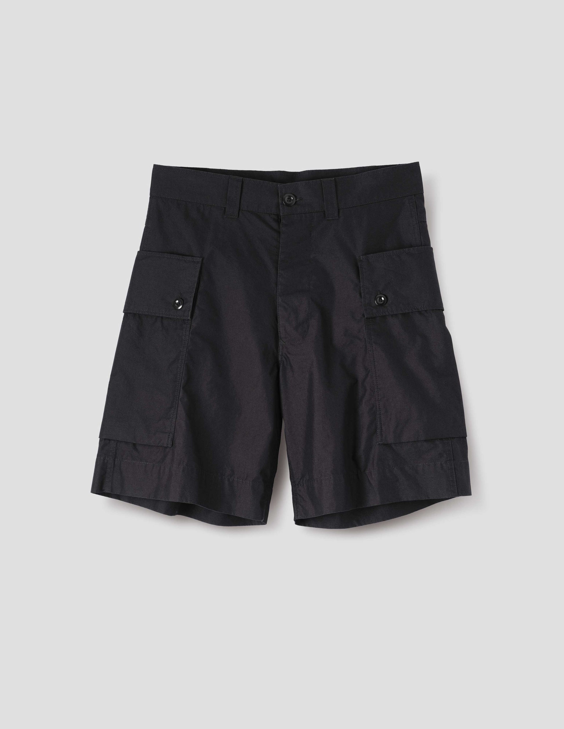 Black cotton shorts with cargo pockets, belt loops and corozo brace button closure. Front flat lay view. 
