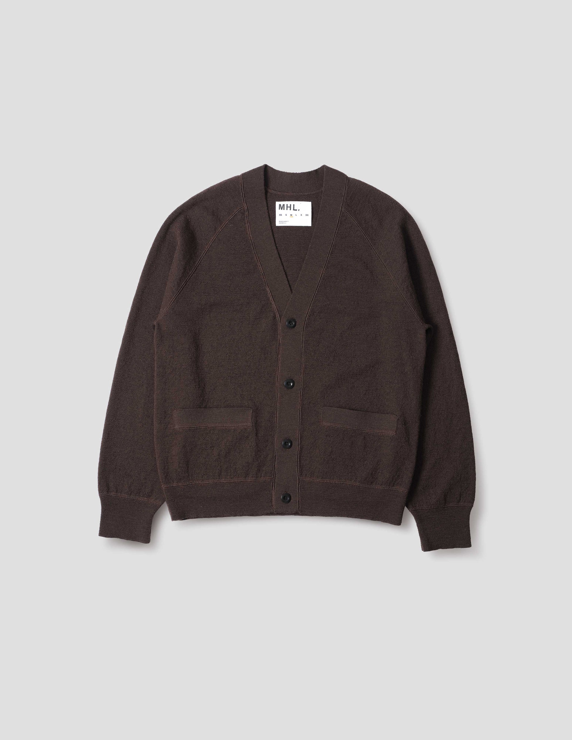 Brown v neck wool cardigan, with concealed pockets, corozo button closure, raglan sleeves and contrast rib on cuffs and hem. Front flat lay view. 