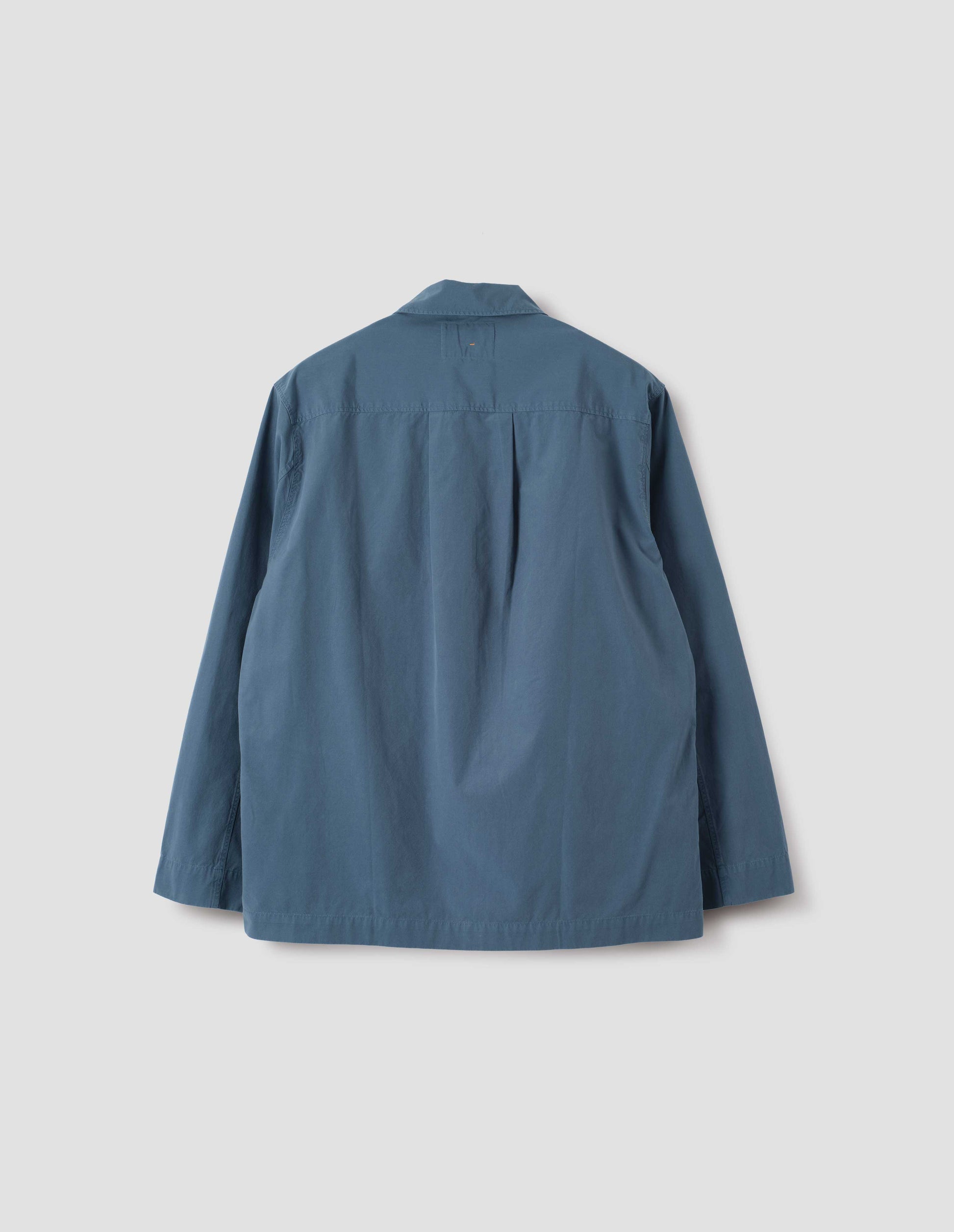 Blue shirt with straight cuffs, side split hem and box pleat on back yoke. Back flat lay view.