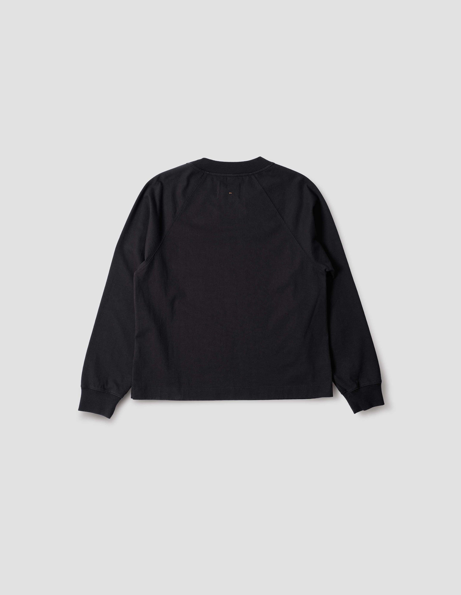 Black cotton long sleeve t-shirt with raglan sleeve, single rib trims on neck and cuffs and vent split hem. Back flat lay view.
