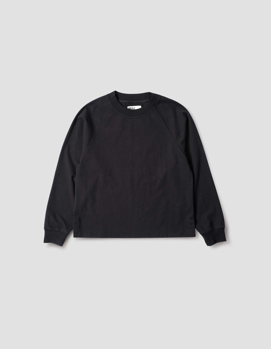 Black cotton long sleeve t-shirt with raglan sleeve, single rib trims on neck and cuffs and vent split hem. Front flat lay view.