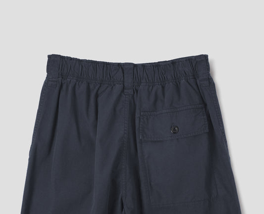 Dark blue trousers with sewn-in patch pockets, half-elasticated waistband, belt loops and corozo brace button fastening flap back pocket. Back flat lay view. 