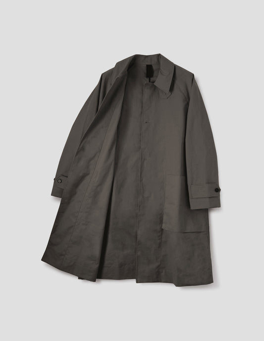 Greyish brown long sleeve cotton mac, with storm tab fastening neck, raglan sleeve, button tab adjustable cuffs and large patch bellow pockets. Front flat lay open view.