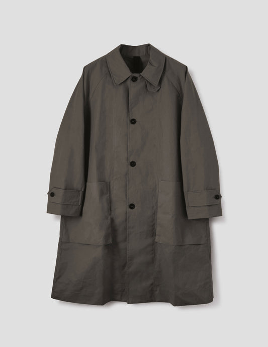 Greyish brown long sleeve cotton mac, with storm tab fastening neck, raglan sleeve, button tab adjustable cuffs and large patch bellow pockets. Front flat lay view.