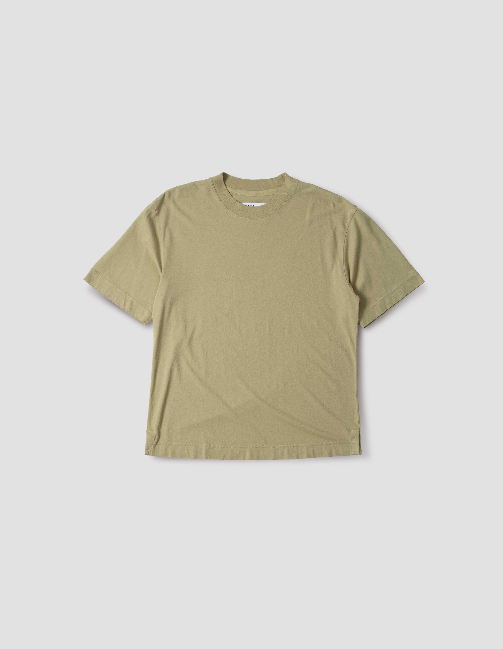 Pale green cotton linen short sleeve t-shirt with vent split hem and herringbone tape detailing inside the neck. Front flat lay view.