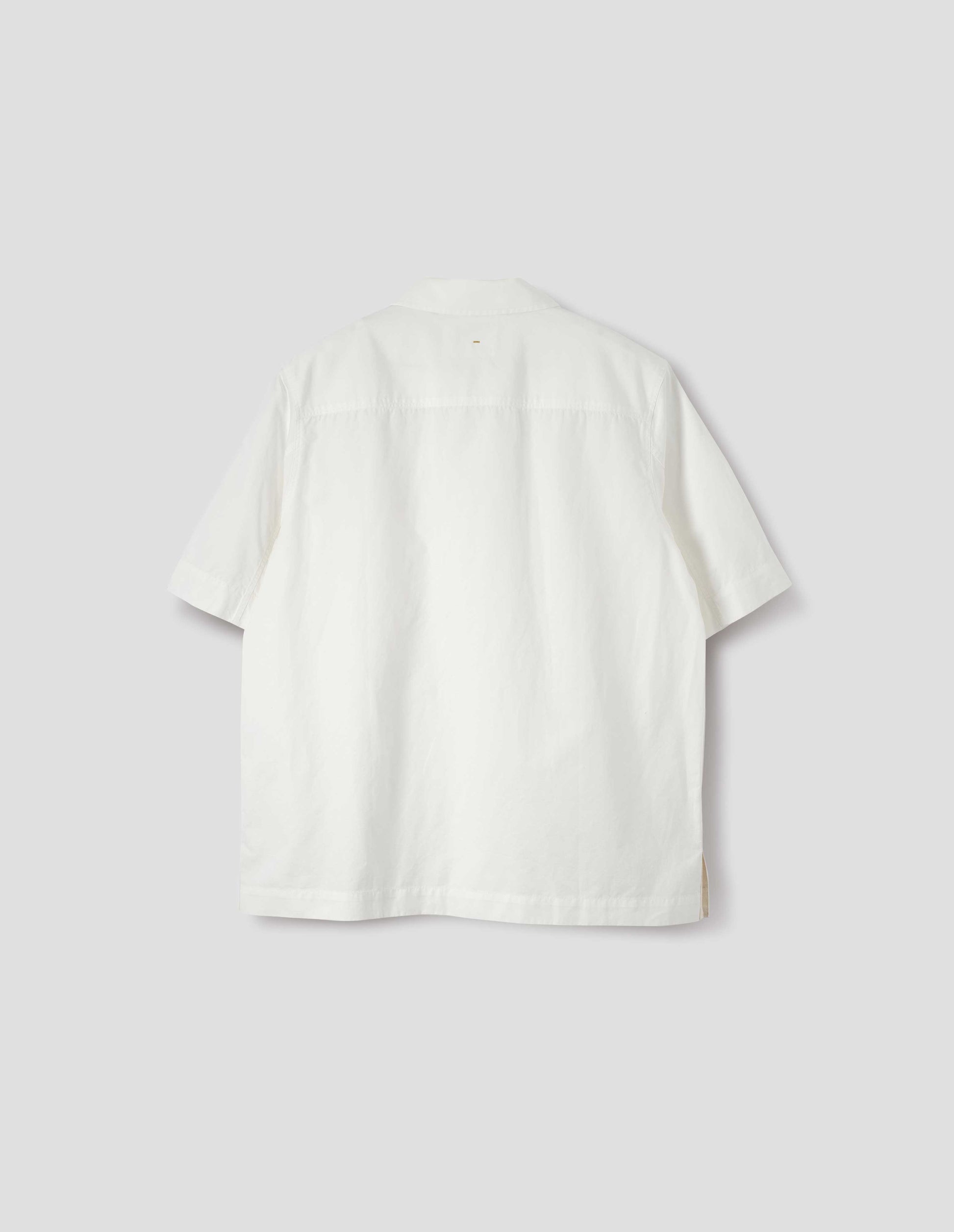 White cotton and linen short sleeve shirt, with side split hem with contrasting herringbone tape. Back flat lay view.