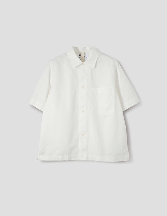 White cotton and linen short sleeve shirt, with large patch chest pocket, side split hem and corozo brace button closure. Front flat lay view.