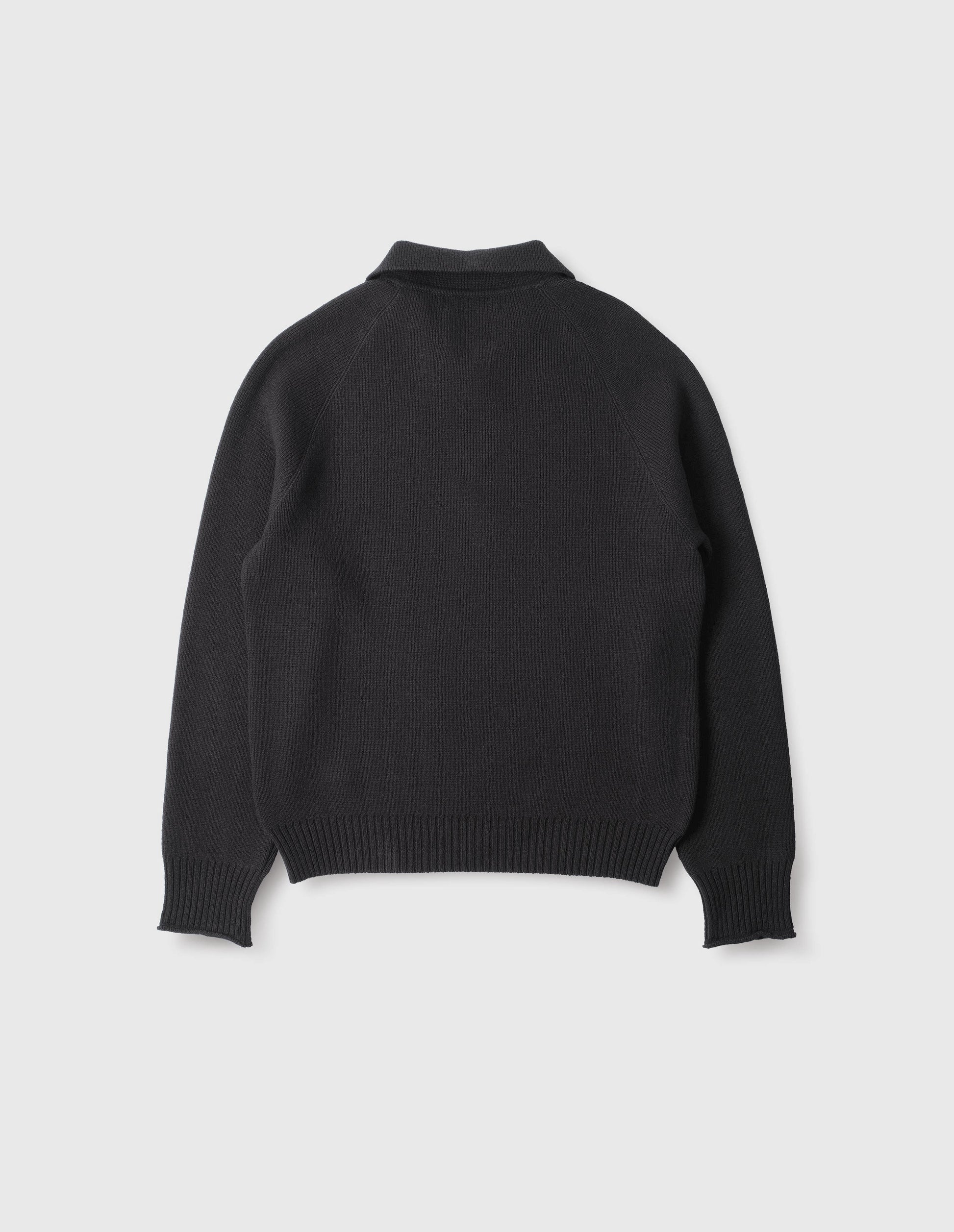 Black wool cotton zip up polo jumper, with raglan sleeve and contrast rib on cuffs and hem. Back flat lay view.