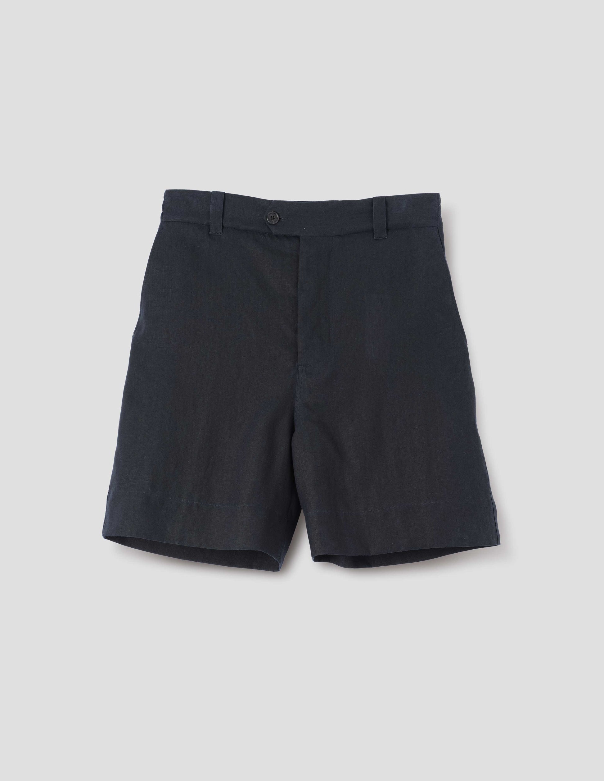 Dark blue shorts with half-elasticated waistband with belt loops, horn button fly with button tab fastening and slant side pockets. Front flat lay view.